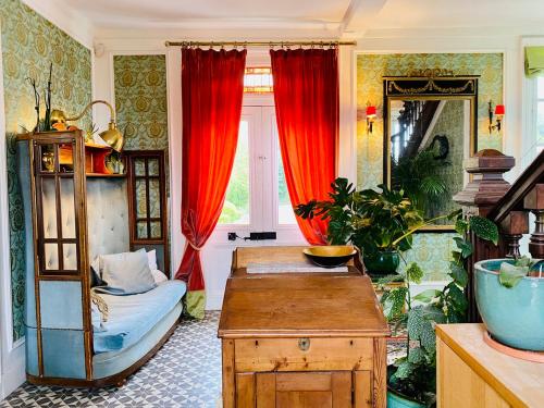 - un salon avec des rideaux rouges et une table dans l'établissement Chambre d’hôtes au Château Le Bas Bleu, Anaïs Nin, à Quesnoy-le-Montant