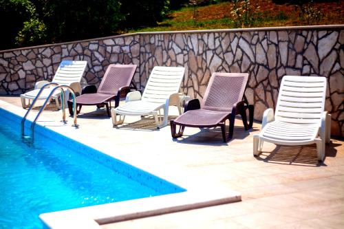 a group of chairs sitting next to a swimming pool at Apartments Villa Iva in Ravni