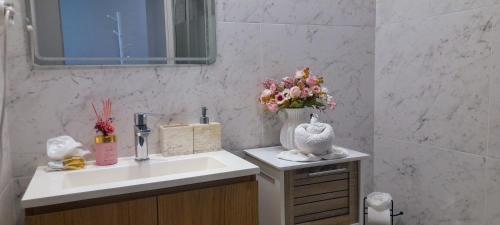 a bathroom with a sink and a vase of flowers at White Design Apartment in Aveiro