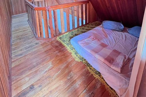 a small bed in a room with a wooden floor at Homestay Wong Kito in Andalas