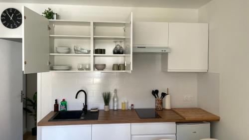 a kitchen with white cabinets and a counter with a sink at L'entracte, T2 rénové ! Jardin, Parking et Fibre in Pau