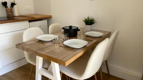 a dining room table with chairs and a wooden table with glasses at L'entracte, T2 rénové ! Jardin, Parking et Fibre in Pau