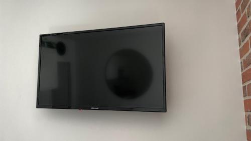 a flat screen tv hanging on a wall at L'entracte, T2 rénové ! Jardin, Parking et Fibre in Pau