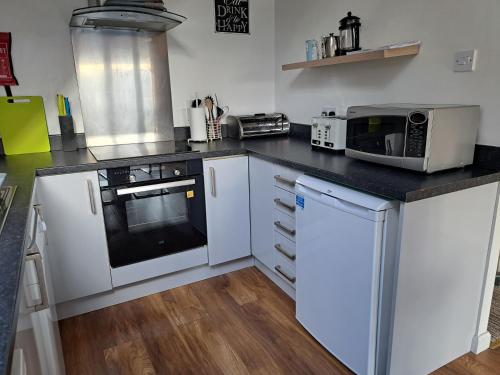 Inchmarlo Golf Resort, Banchory Villa 26 AS 00266F في بانشوري: مطبخ بخزائن بيضاء وطاولة عمل سوداء