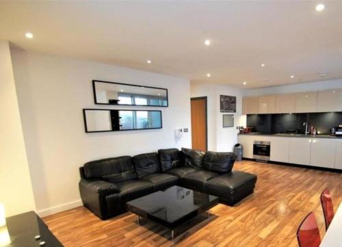 a living room with a black leather couch and a kitchen at London Dockside 3 Bed in London
