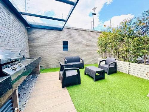 a patio with chairs and a grill and grass at Domus Suites Chia in Chía
