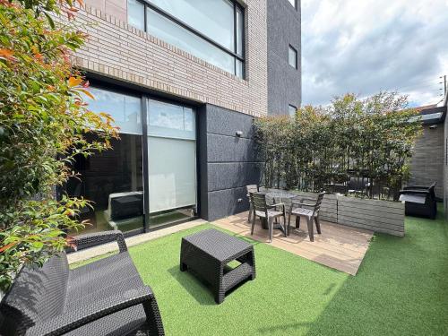 a patio with a table and chairs and grass at Domus Suites Chia in Chía