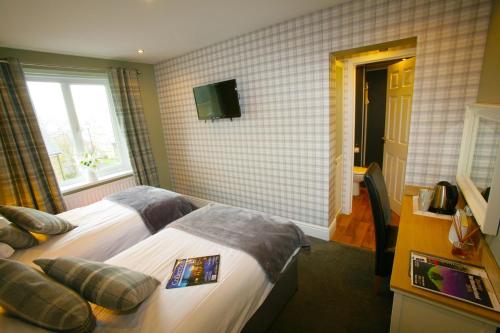 a hotel room with two beds and a television at The Sunningdale in Bamburgh
