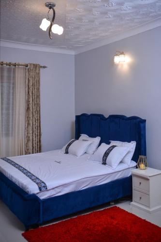 a blue bed in a room with a red rug at Doreens Villa in Wakiso