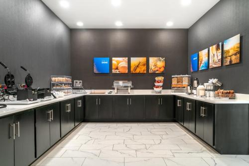 a kitchen with black cabinets and white counter tops at Comfort Inn & Suites Adrian in Adrian