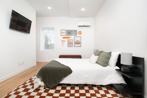 a white bedroom with a bed and a checkered floor at Modern Cityscape Downtown Knoxville in Knoxville