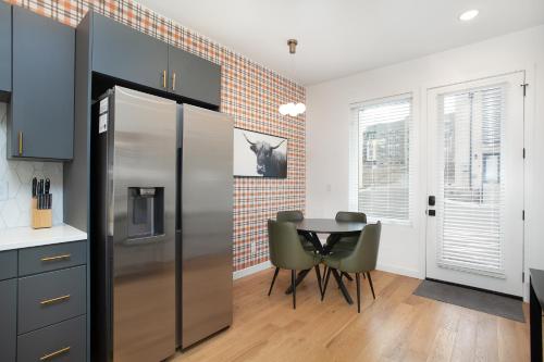 a kitchen with a table and a stainless steel refrigerator at Modern Cityscape Downtown Knoxville in Knoxville