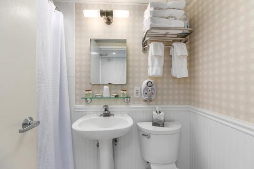a bathroom with a sink and a toilet and a mirror at Pan American Oceanfront Hotel in Wildwood Crest