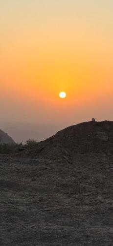 a sunset in the desert with the sun on a hill at Sunset view hill jabal shams in Misfāh