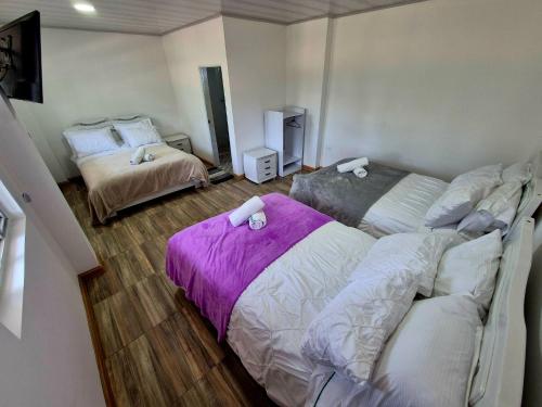 a bedroom with two beds with purple sheets at Hotel Villa Isabella Esperanza de Tinjacá Boyacá in Tinjacá