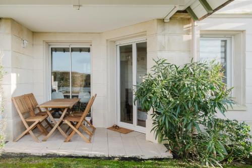 une terrasse avec une table et des chaises en bois sur une maison dans l'établissement Bord de mer, Jardin privé, 100 m de la mer, à Tourgéville