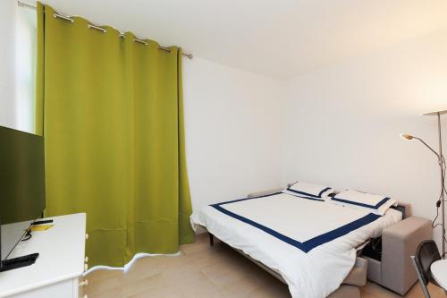- une chambre avec un lit et un rideau vert dans l'établissement Studio Rimbaud - Festival-Center-Clim-Wifi, à Cannes