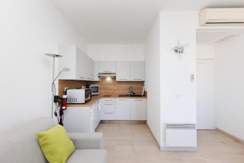 - une cuisine avec des placards blancs et un oreiller jaune dans l'établissement Studio Rimbaud - Festival-Center-Clim-Wifi, à Cannes