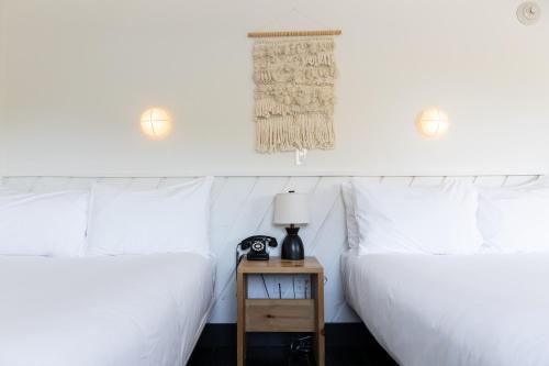 two beds with white sheets and a night stand with a lamp at Scribner's Catskill Lodge, a Member of Design Hotels in Hunter