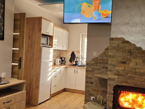 una cucina con camino e TV sopra di Domki Magiczne Miejsce a Hużele