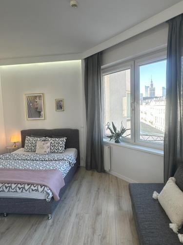 a bedroom with two beds and a large window at Exclusive Apartments Smolna in Warsaw