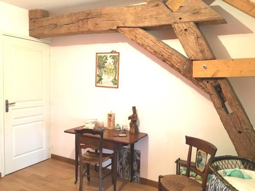 Cette chambre dispose d'une table et d'un plafond en bois. dans l'établissement Charmante ferme vue exceptionnelle 10 voyageurs, à La Grande-Verrière