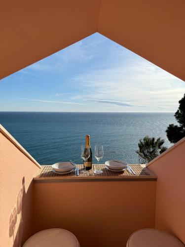 una mesa con una botella de vino y copas en el balcón en Nido Sul Mare, en Ventimiglia