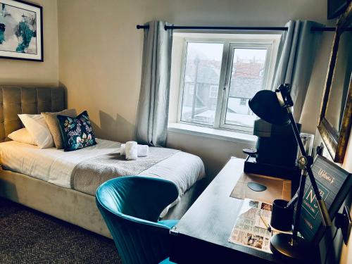 a bedroom with a bed and a desk and a window at Hotel No5, Beachfront with Free Private Car Park in Llandudno