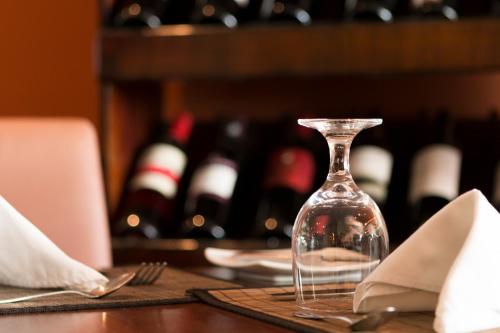 a wine glass sitting on top of a table with wine bottles at Rincon del Valle Hotel & Suites in San José