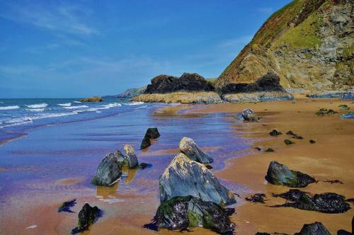 a beach with rocks in the sand and the ocean at Cwtch Ffynnone Luxury Shepherds Hut in Newchapel