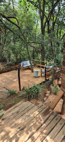 a wooden deck with two benches and trees at Piece of EDEN in Skeerpoort