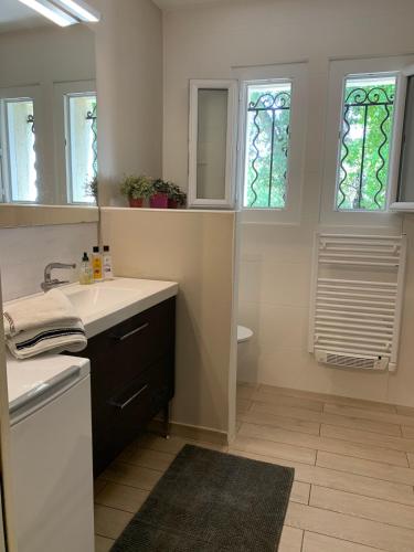 une salle de bain avec un lavabo et deux fenêtres dans l'établissement Villa with large spacious apartment, Privatized with big garden and swimming pool, à Beaulieu