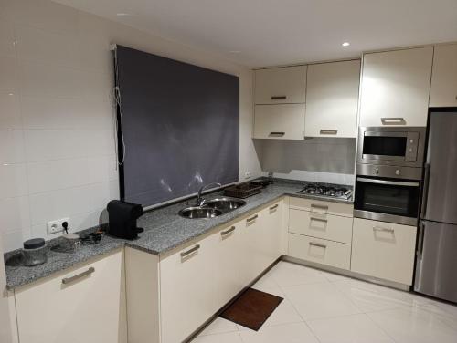 a kitchen with white cabinets and a stainless steel refrigerator at Elly Apartamentos in Mindelo