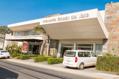 uma carrinha branca estacionada em frente a um edifício em Rincon del Valle Hotel & Suites em San José