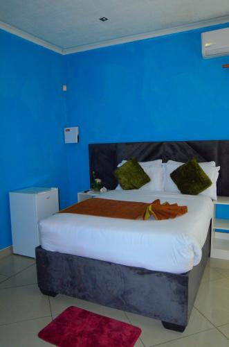 a bedroom with a large bed with a blue wall at Chobe Kulotu Guest House in Kasane