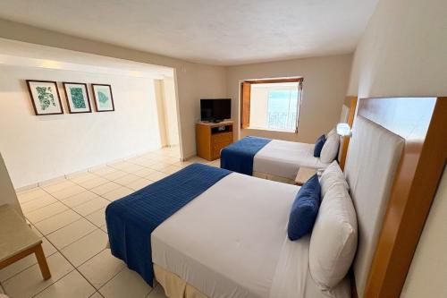 a hotel room with two beds and a television at Oceanfront with exclusive amenities! in Puerto Vallarta