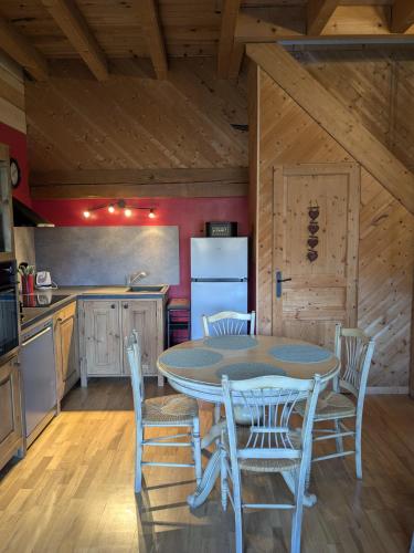 une cuisine avec une table, des chaises et un réfrigérateur dans l'établissement La Grange, à Le Noyer