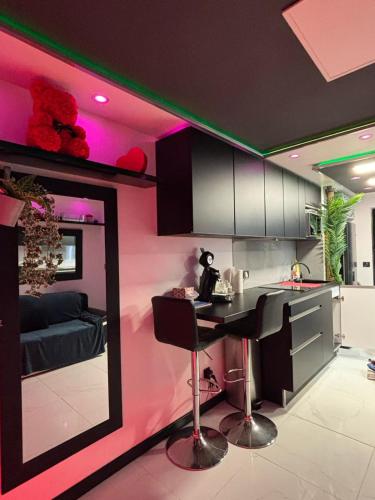 une cuisine avec des murs roses et un comptoir avec une table dans l'établissement C12 Deluxe, au Cap d'Agde