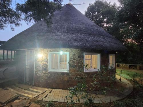 a small stone house with a thatched roof at Piece of EDEN in Skeerpoort