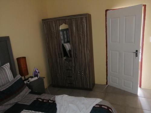 a bedroom with a large wooden cabinet and a bed at TRAVELASPA Guest House in Roodepoort