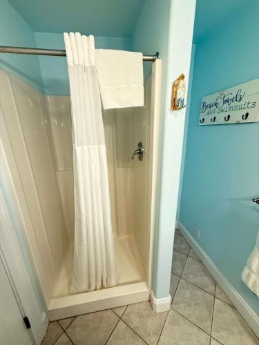 a shower with a white shower curtain in a bathroom at Island Guesthouse and Motel OBX in Manteo