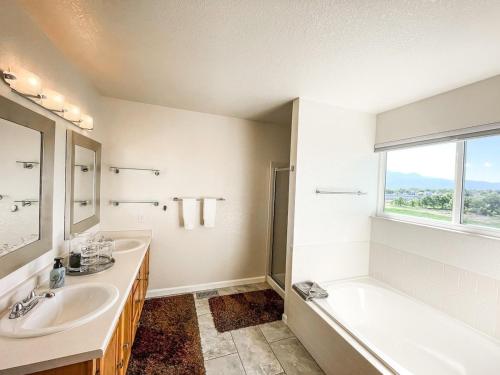 Un baño con dos lavabos y una bañera y una ventana. en Trailside Getaway - mins to Ft Carson & Airport, en Fountain