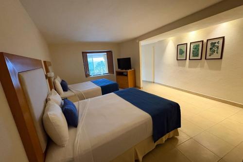 a hotel room with two beds and a television at Ocean view & direct beach access! in Puerto Vallarta