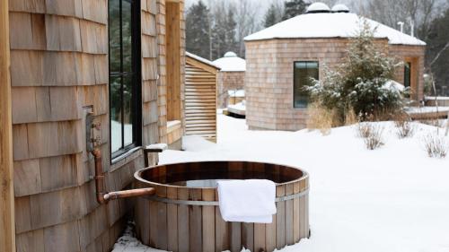 a hot tub in the snow next to a house at Scribner's Catskill Lodge, a Member of Design Hotels in Hunter