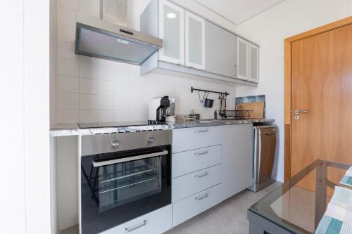 a kitchen with white cabinets and a stove top oven at Green & Sea Comporta Retreat in Comporta