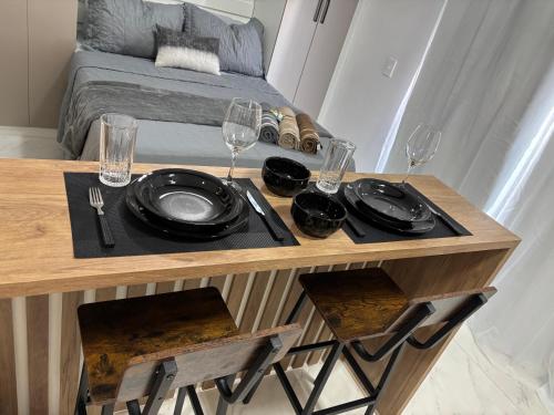 a table with plates and wine glasses on it at Studio Carmenere Com varanda e vista incrível Mogi das Cruzes in Mogi das Cruzes