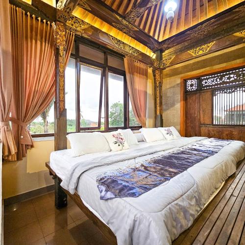 a large bed in a room with windows at Villa Djojonagoro in Ketewel