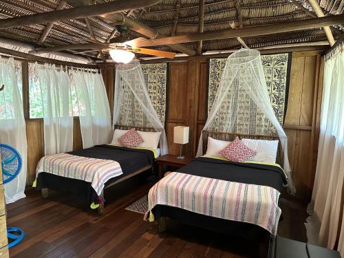 two beds in a room with curtains and wooden floors at Creekside Oasis in San Felipe