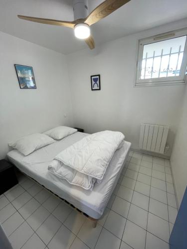 une chambre avec un lit avec des draps blancs et une fenêtre dans l'établissement Plages & Marina - joli T2 à 200m des plages Sète, à Sète