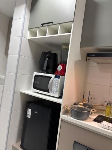 a small kitchen with a microwave and a refrigerator at Studio Carmenere Com varanda e vista incrível Mogi das Cruzes in Mogi das Cruzes